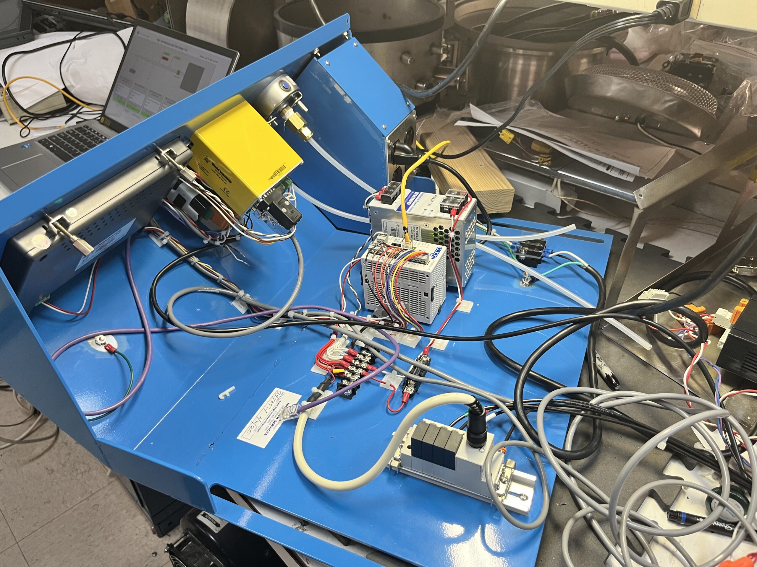 Interior of the leak test system's control cabinet showing the Click PLC, terminal block wiring, power supply, and pneumatic solenoid valve manifold